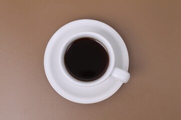 Black coffee in a white cup on a brown table