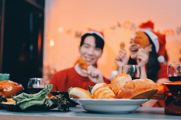 Group of young Asian man and women as friends having fun at a New Year's celebration, holding gift boxes standing by Christmas tree decoration, midnight countdown Party at home with holiday season.