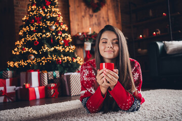 Photo of positive adorable cute woman dressed new print clothes lying on carpet christmas weekend drink eggnog indoors