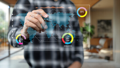 Fototapeta premium Business professional analyzing global data trends on a digital touchscreen, showcasing interactive world map with statistics and colorful graphs in modern office environment