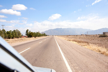 Scene of a trip through the Andes as seen from a car: road heading towards the mountains in Mendoza, Argentina.