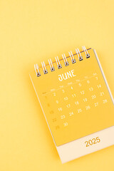 Yellow desktop calendar for June 2025 on a yellow background.