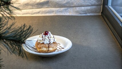 Papanasi is a delicious dessert made of dough, topped with sweet cream, a cherry, and a drizzle of chocolate, perfect for festive celebrations or cozy gatherings