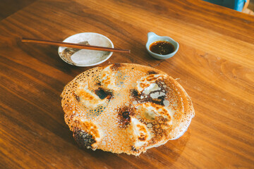 Japanese fried dumplings served on a round plate with sauce.