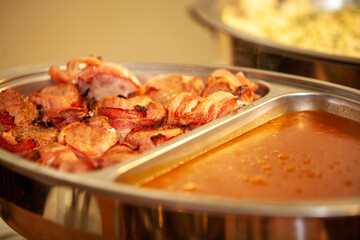 An inviting and tempting display of crispy bacon along with a savory sauce presented beautifully at a catering event
