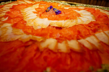 A brightly colored, vibrant salmon carpaccio, elegantly garnished with edible flowers, ideal for...