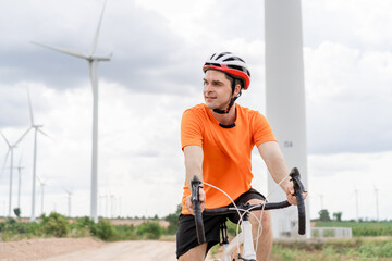 Caucasian active sportsman riding bicycle at the wind turbine field. 
