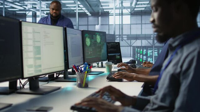 Programmer seeing red critical error popup on computer display in data center, panicking. African american man in server hub spamming keyboard buttons after receiving error, camera A