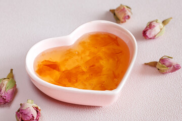 Homemade jam of rose petals in heart shape bowl on pink background. Traditional Turkish dessert. Selective focus.