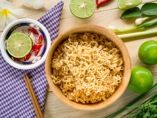 Instant noodles in wooden bowl and vegetable side dishes on wood background