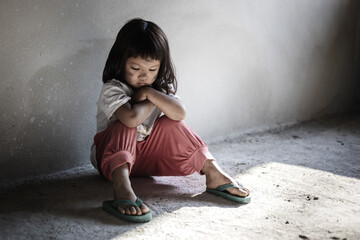 Poor stress child girl sitting in dark room. traumatized young girl