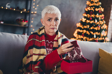 Photo of nice aged woman sullen face open socks gift box christmas festive illumination apartment...