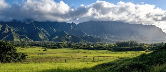 Fototapeta premium Majestic mountain landscape under dramatic clouds with lush green fields in the foreground showcasing the beauty of nature.