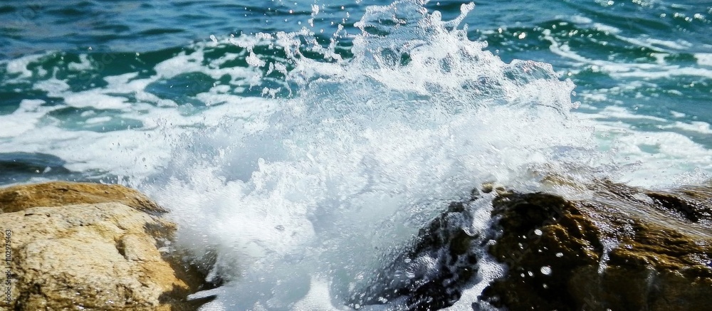 Aufkleber dynamic seascape of waves crashing against rugged shoreline creating a frothy spray and capturing th