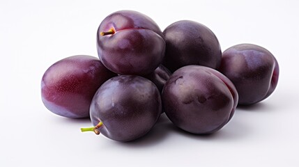 Obraz premium Fresh plums piled elegantly on a pristine white background showcasing their rich color and natural shine ideal for food-related projects.