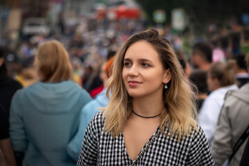 A young beautiful girl walks the floor of a city street against the traffic of the crowd. concept of going against crowd, swimming against current. A blonde against a background of many blurred people