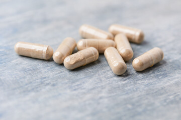 Reishi capsules. Concept for a healthy dietary supplementation. Wooden background. Soft focus. Close up