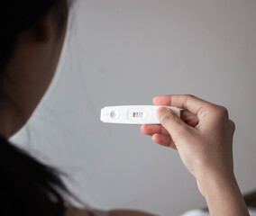 Woman holding a positive pregnancy test in her hand. Selective focus.