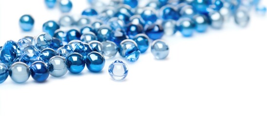 Fototapeta premium Blue and silver decorative beads scattered on a white background showcasing texture and color variety for crafting and design purposes