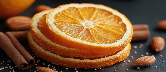 Dried orange slices with cinnamon sticks and almonds arranged on a dark background for a warm and inviting culinary presentation