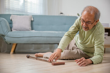Sick senior old man falling down lying on floor because stumbled at home alone with wooden cane...
