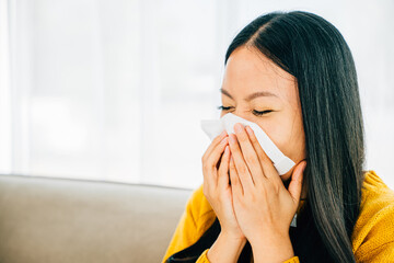 A woman at home holding a tissue experiencing symptoms like coughing and stuffy nose. Portrait of a patient dealing with illness. Snot and handkerchief in hand.