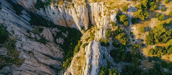 Fototapeta premium aerial view of rugged cliff landscape with greenery and rocky formations under bright sunlight