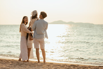 happy family, family, beach, vacation, summer, happy, relaxation, fun, together, kids. A family of three, a man and two women, are standing on a beach. Scene is happy and relaxed.