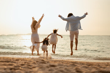 happy family, family, beach, vacation, summer, happy, relaxation, fun, together, kids. A family of four is playing in the sea, Scene is joyful and carefree.