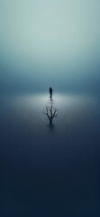 Fototapeta premium Solitary Contemplation - A tranquil scene on a rainy lake, featuring a single tree and a solitary figure.