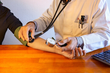 Visit to the GP's office. Doctor in lab coat measures a patient's blood pressure. Healthcare....