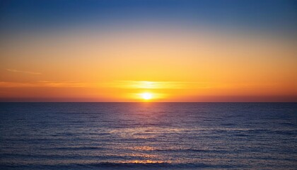 Fototapeta premium Golden Hour Horizon: A serene and captivating view of the sun setting over a vast ocean, painting the sky in vibrant hues of orange and blue. The horizon stretches endlessly.