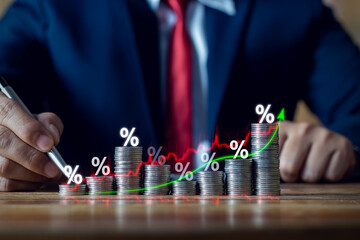 Businessman putting down money, pointing with pen and showing candlestick symbol for investing, finance, saving money, interest rate or dividend investment, business growth concept.