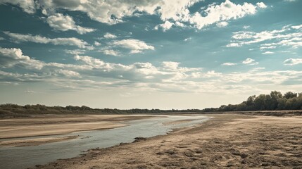 A desolate landscape showcasing dry, cracked earth and barren riverbanks under a dramatic sky, emphasizing the impact of drought on the environment.