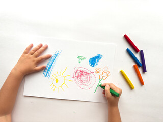 Childs colorful crayon drawing with bright sun, flowers, and geometric shapes on white paper