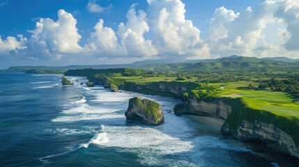 Aerial view of dramatic coastal cliffs with lush green grass, ocean waves crashing below, under a bright blue sky filled with fluffy white clouds.