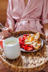 Comfortable bed, breakfast in bed. female hands hold a wooden tray with apple pie and fresh strawberries.
