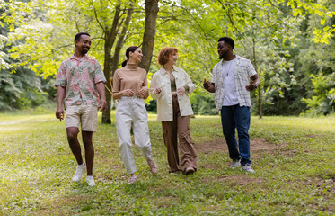 Fototapeta premium Multiracial friends walking and talking in a park during summer vacation