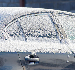 A car is covered in snow and the windshield is frosted over