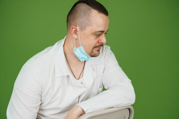 Male Medical Professional in White Coat with Surgical Mask Against Green Background