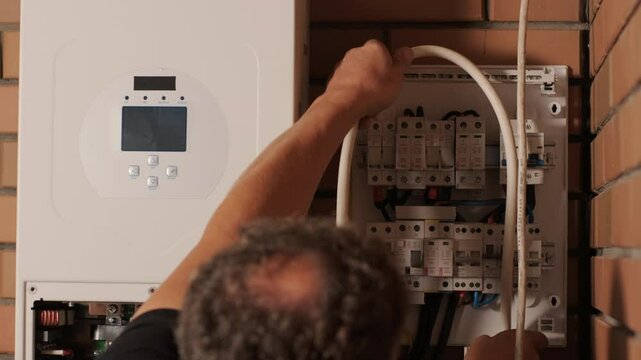 An electrician installing an inverter in a home. The image shows technical skill, modern tools, and attention to safety in electrical work