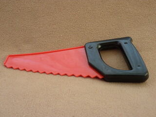 A Vibrant Toy Saw on a Neutral Backdrop: Symbolizing a Child’s First Steps in Building Creativity...