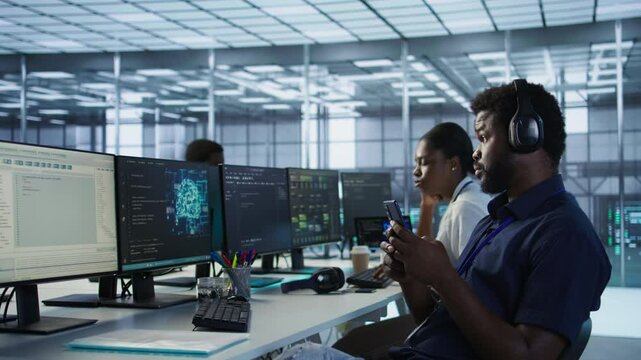 Admin in server room using mobile phone, relaxing after ensuring minimal downtime. Data center IT expert texting on smartphone, taking break from monitoring performance, camera A