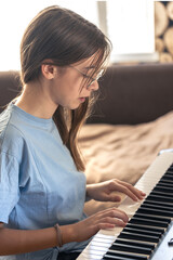 A beautiful girl plays the piano. Playing the piano and musical instruments.