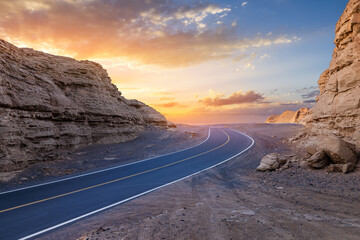 Asphalt road and Yardang landform mountain natural landscape at sunrise in Xinjiang, China. road trip.