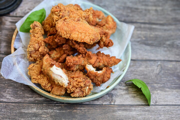 
 Crispy home made  deep fried   chicken strips . Breaded  with cornflakes chicken  breast fillets  with chilly peppers and fresh   basil on wooden rustic background