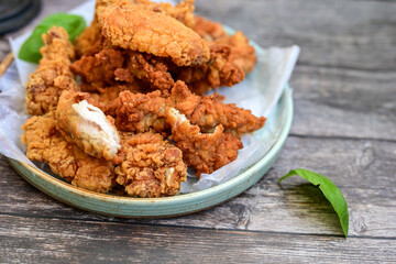 
 Crispy home made  deep fried   chicken strips . Breaded  with cornflakes chicken  breast fillets  with chilly peppers and fresh   basil on wooden rustic background