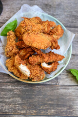 
 Crispy home made  deep fried   chicken strips . Breaded  with cornflakes chicken  breast fillets  with chilly peppers and fresh   basil on wooden rustic background