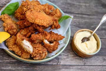
 Crispy home made  deep fried   chicken strips . Breaded  with cornflakes chicken  breast fillets  with chilly peppers and fresh   basil on wooden rustic background