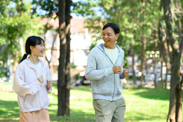 Active senior man and his daughter wearing athletic clothing enjoy their morning run in the fresh air